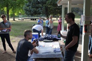 A photo of two white men outside at a picnic table talking.