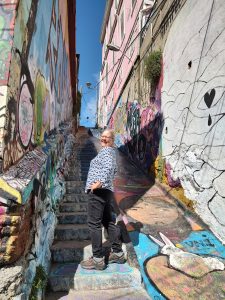 A photo of a white woman standing on stone stairs and looking back at the camera