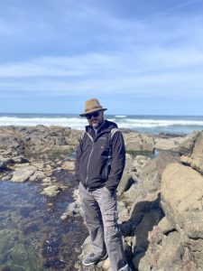 A picture of a white man standing on a rocky coastline