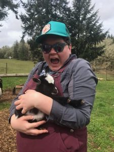 A photo of a white woman holding a baby goat